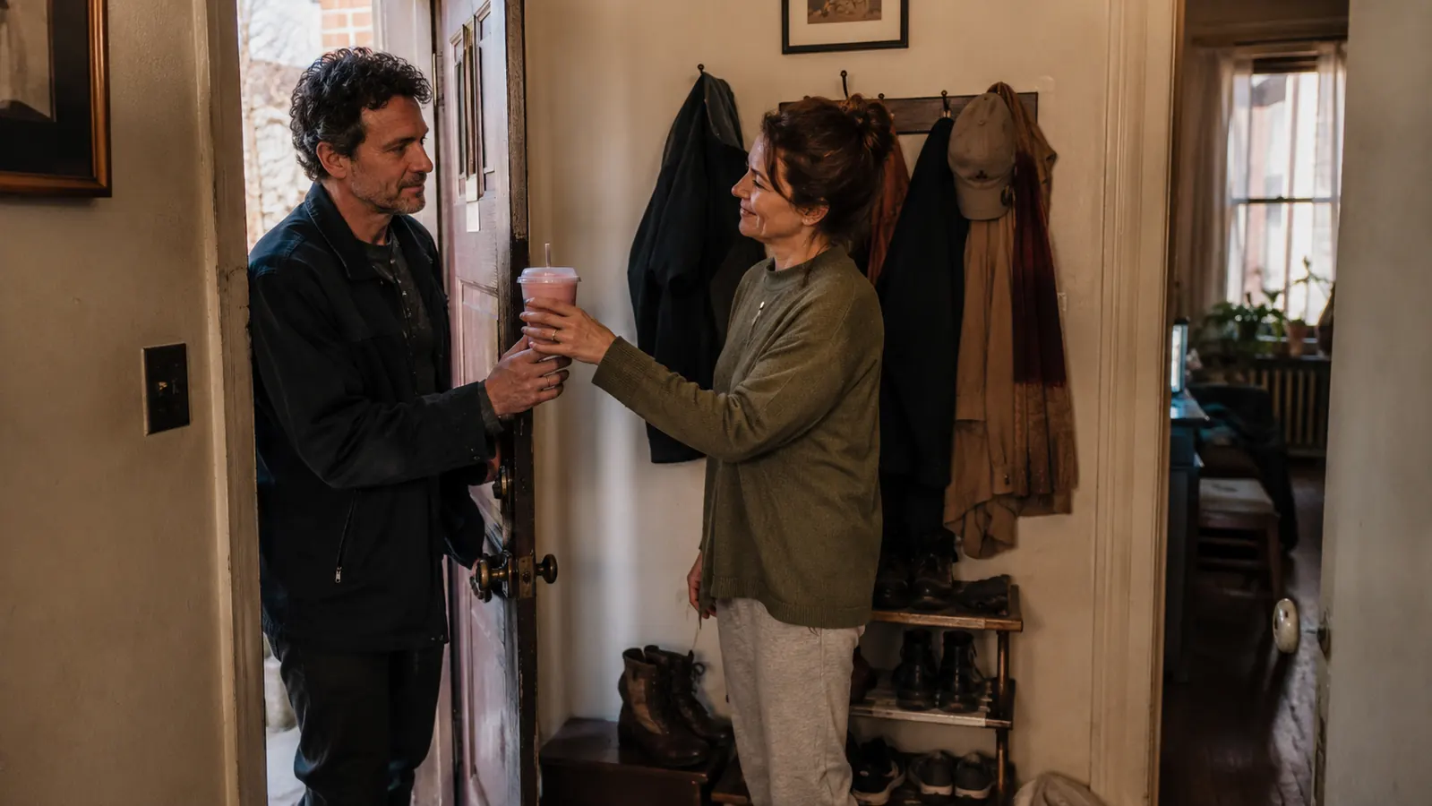 Woman handing a single-serve smoothie cup to her husband as they head out the door in the morning