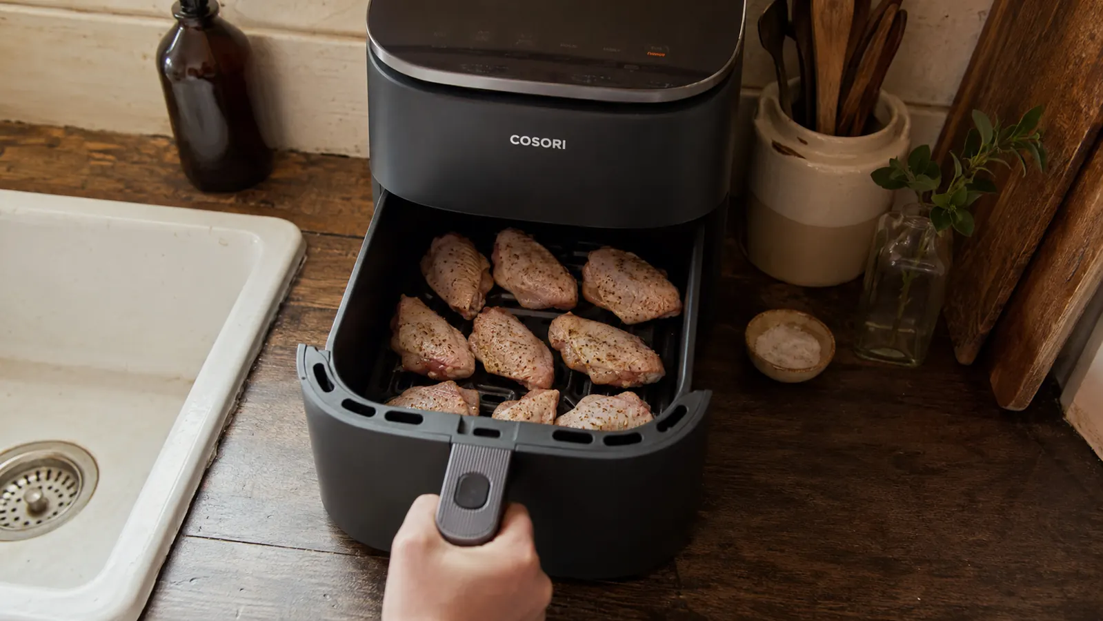 Overhead view of raw seasoned chicken wings arranged in a single layer inside the Cosori Air Fryer Pro's ceramic basket