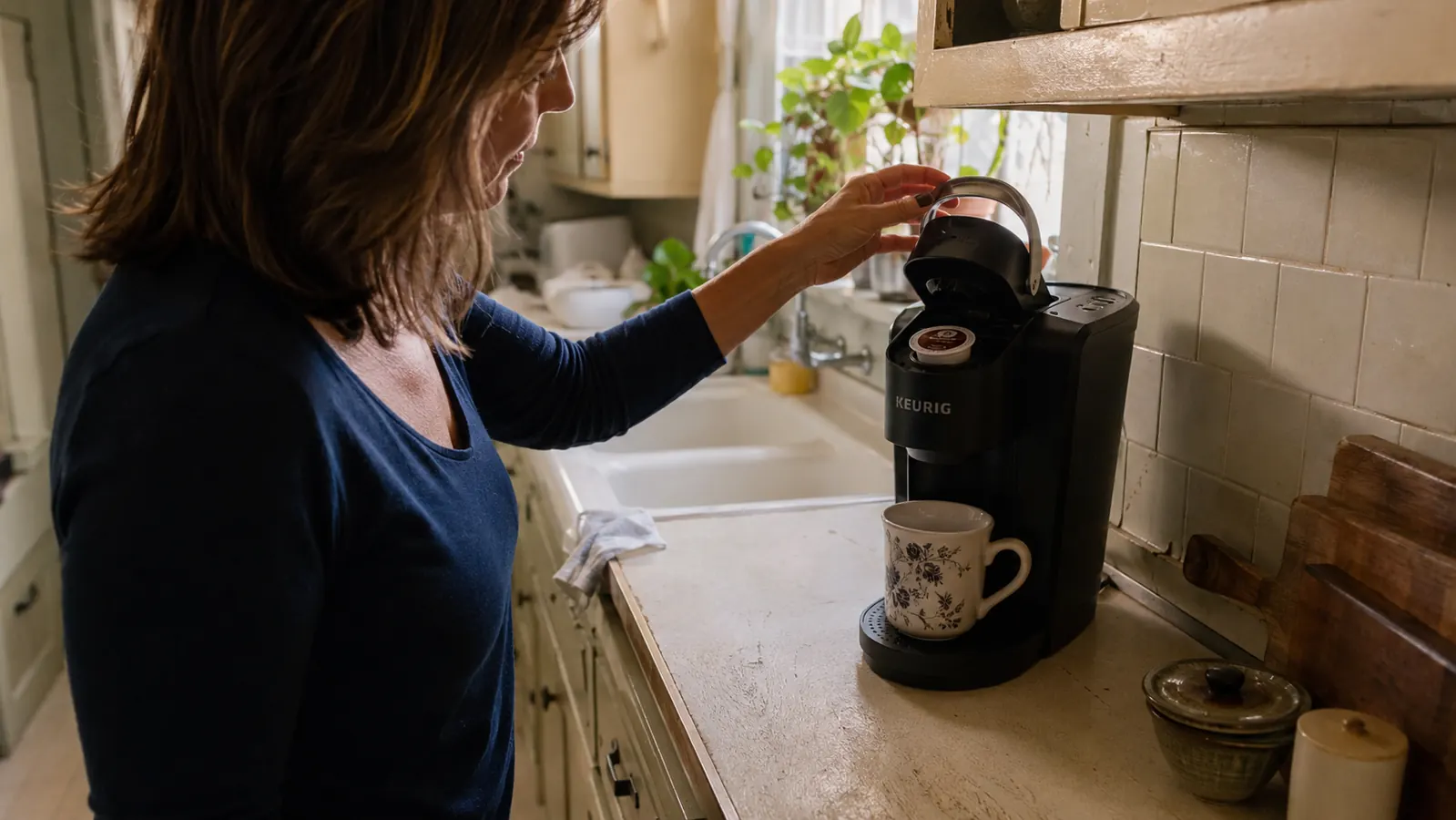A hand loading a K-Cup pod into the top of the Keurig K-Classic