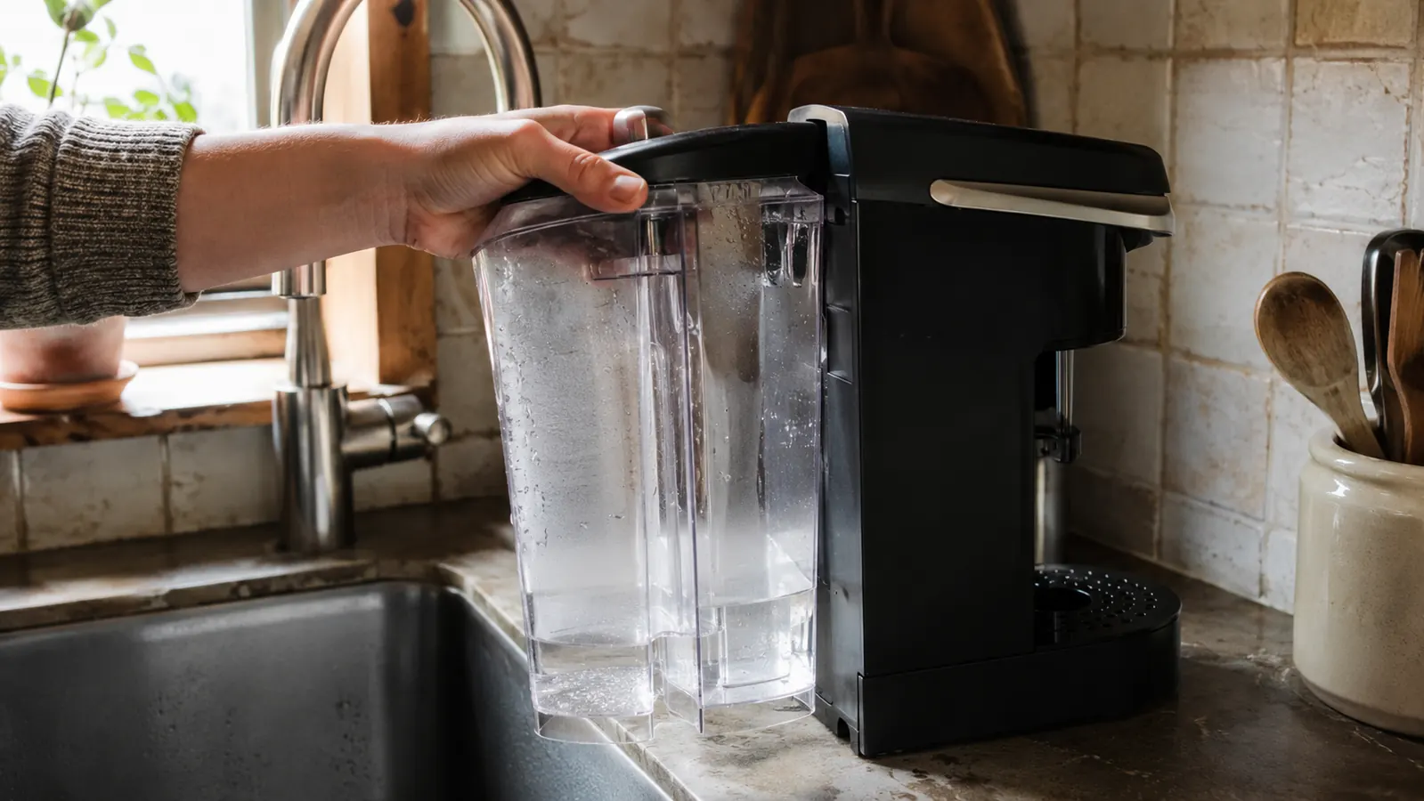 A hand removing the water reservoir from the Keurig K-Classic to refill it