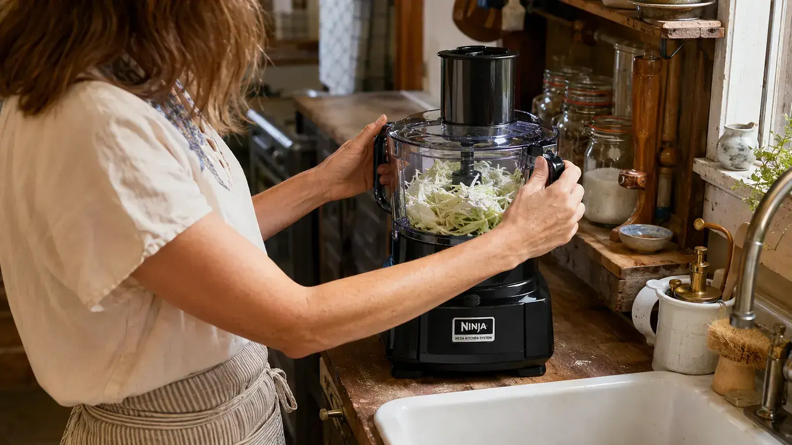 Hands attaching the food processor bowl to the Ninja Mega Kitchen System base